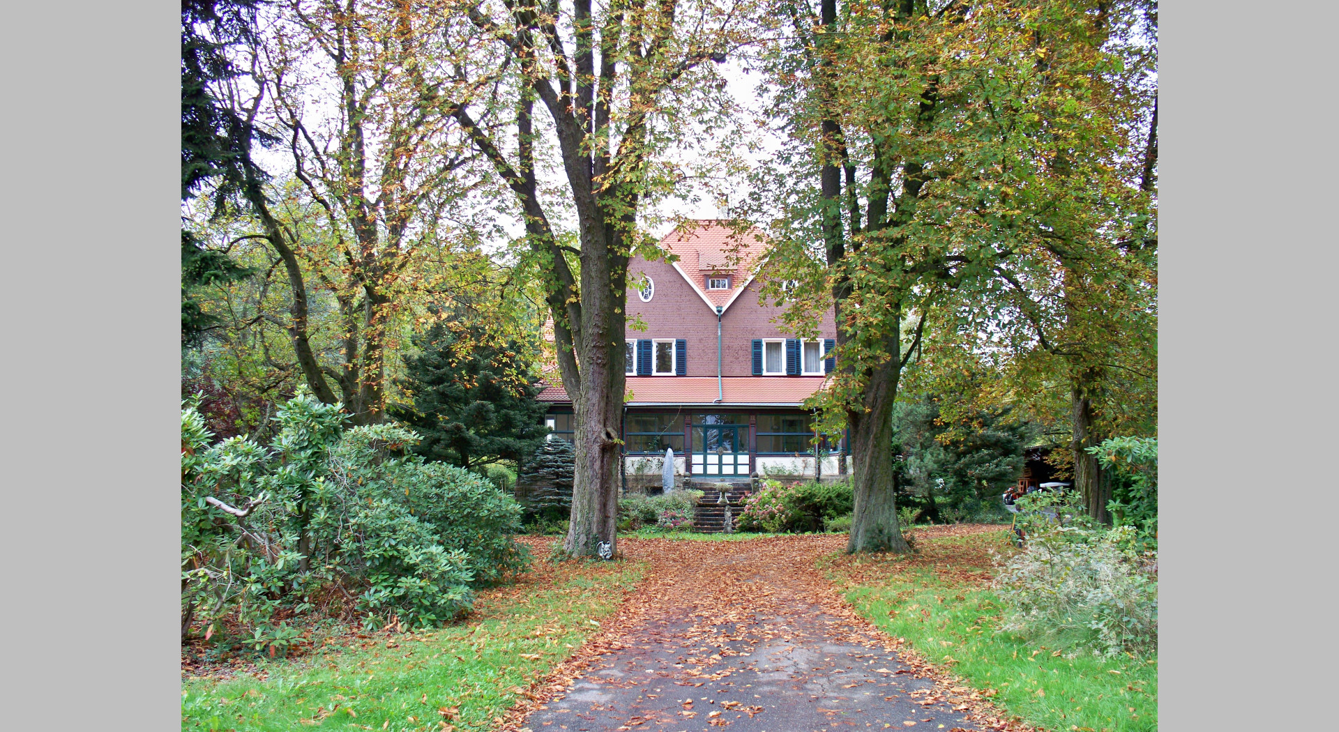 Das Bild zeigt die Frontansicht unseres Hauses von der Straße her kommend. Es zeigt die Auffahrt sowie den an der Frontseite des Hauses gelegenen Wintergarten.