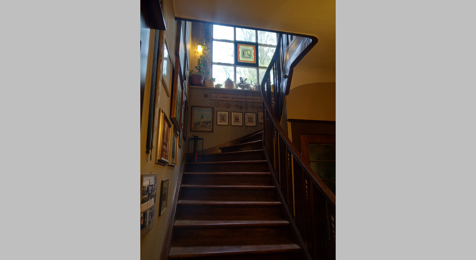 Blick entlang der innenliegenden Eichenholztreppe vom EG ins 1. OG. Großes rückseitiges Kassettenfenster sichtbar.