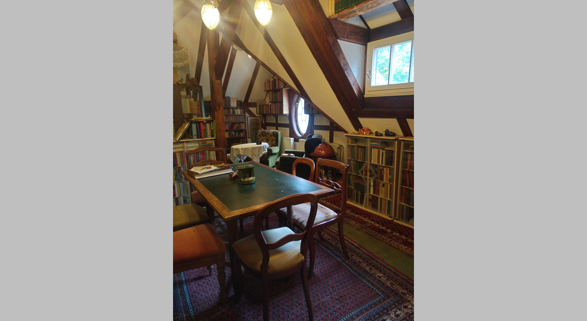 Blick auf die linke Seite der Bibliothek im 2. OG mit Spieltisch und Bücherregalen