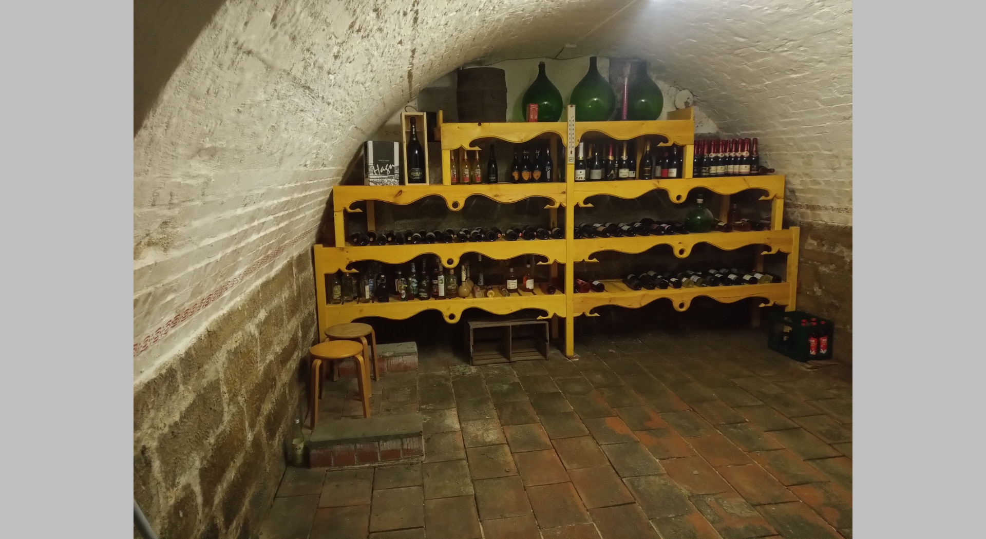 Blick in den Weinkeller mit kleinem Rundgewölbe und Tonfliesen auf gestampftem Lehmboden