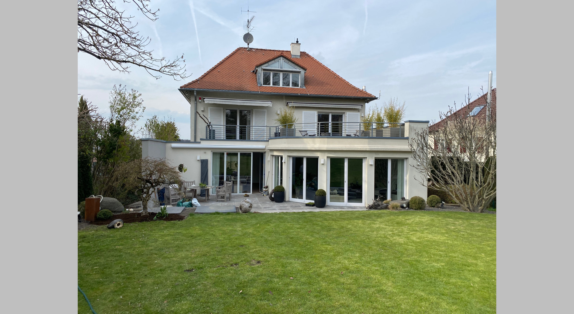 Man sieht einen ebenen Rasen und das Haus von der Südseite 