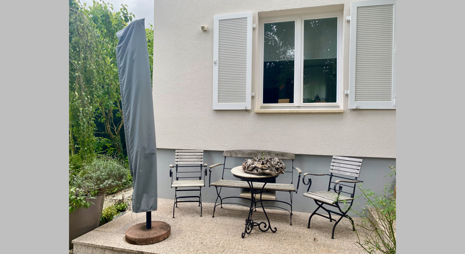 Man sieht ein Fenster mit Klappläden und einen kleinen Sitzplatz