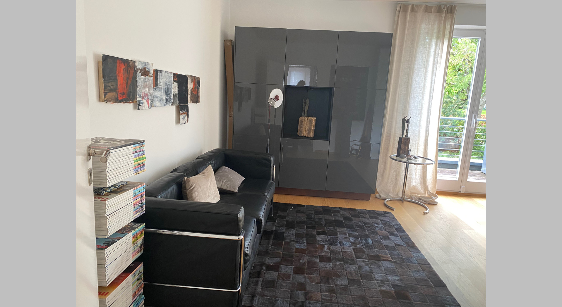 Schwarzes Le Corbusier Sofa und grauer Lackschrank im rechten Büro