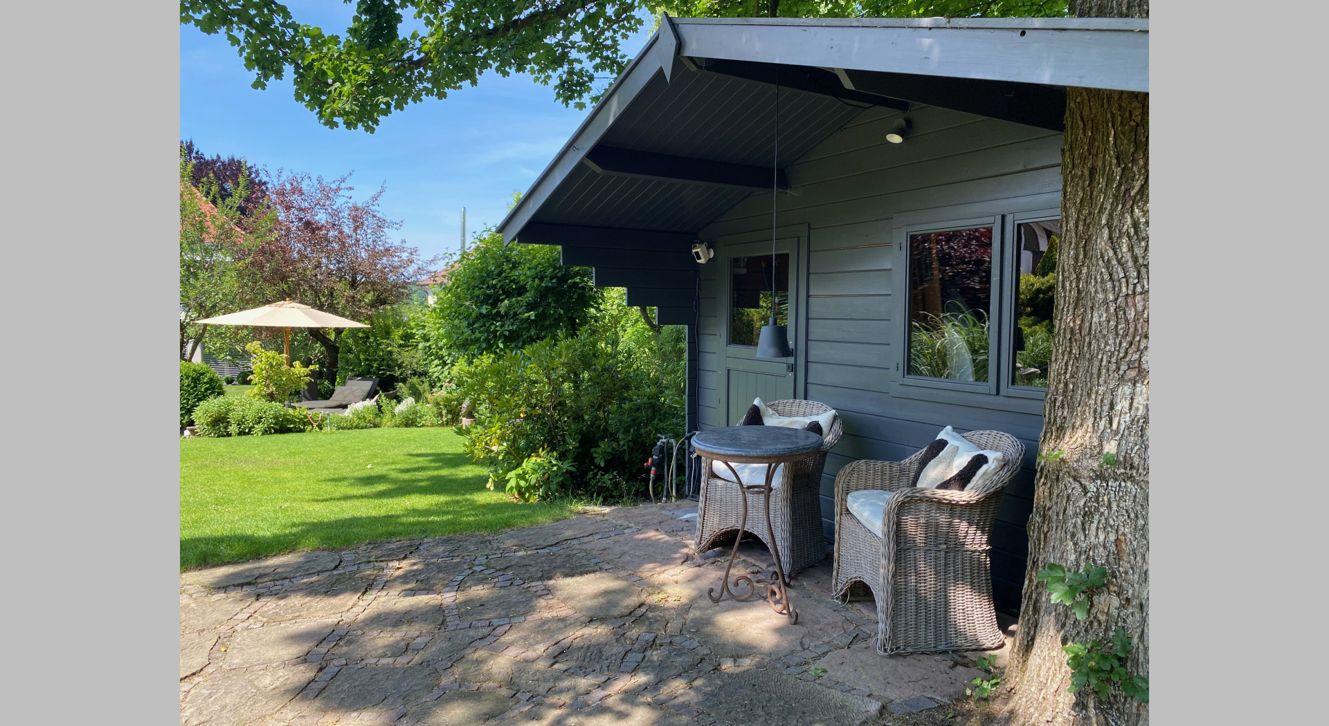 Ein Gartenhaus mit kleinem Sitzplatz im hinteren Gartenteil