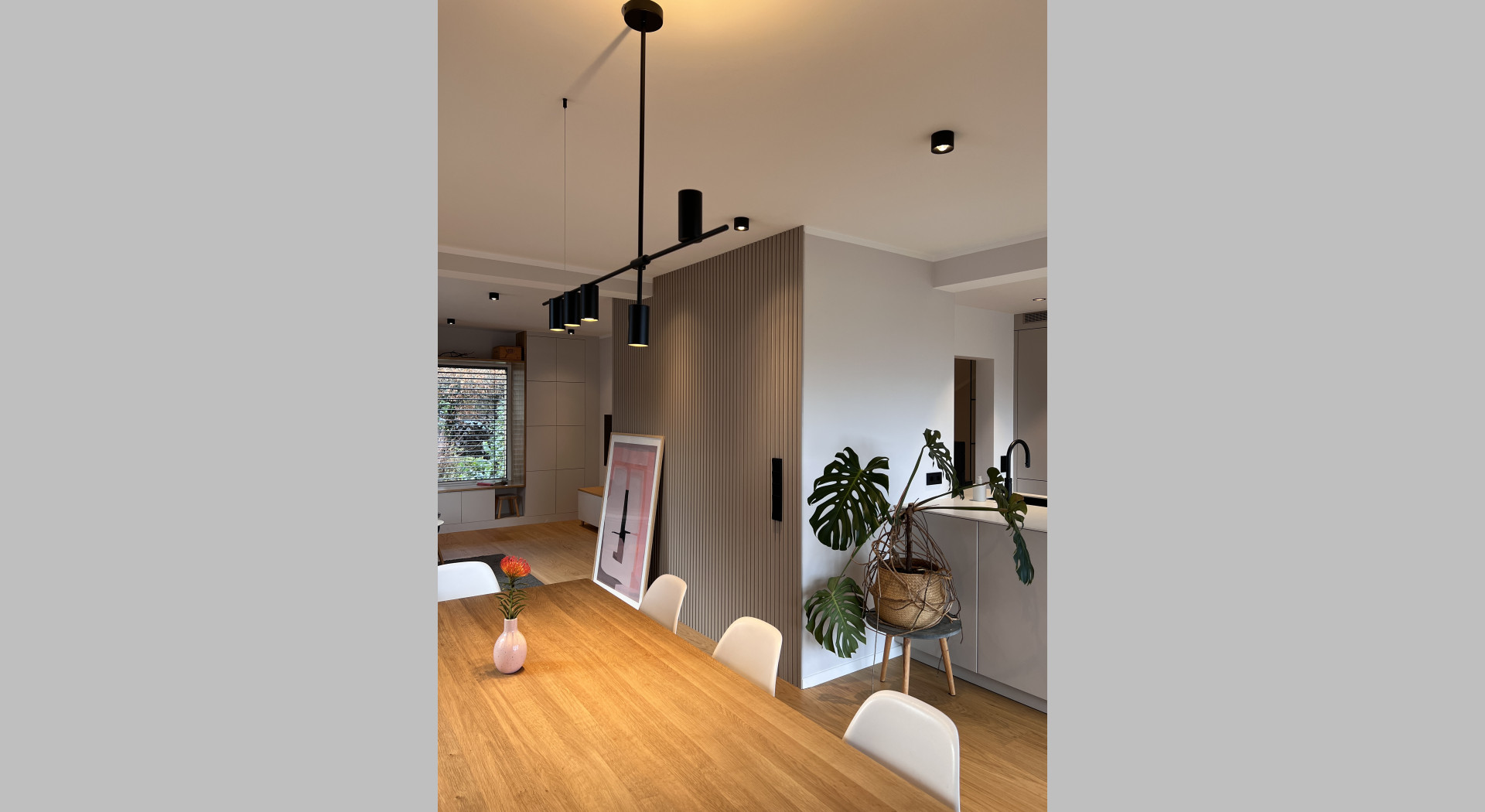 Wohn- und Esszimmer mit großem Holztisch und offener Küche