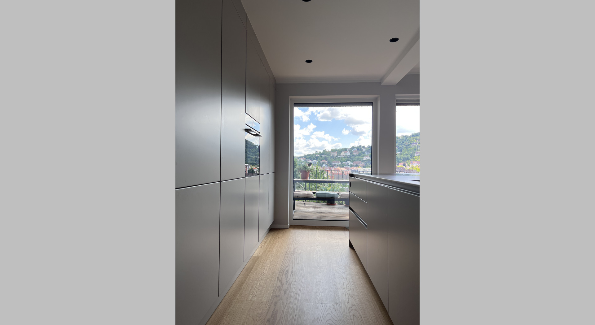 Sandgraue, moderne Küchenfronten mit Blick auf ein großes Fenster