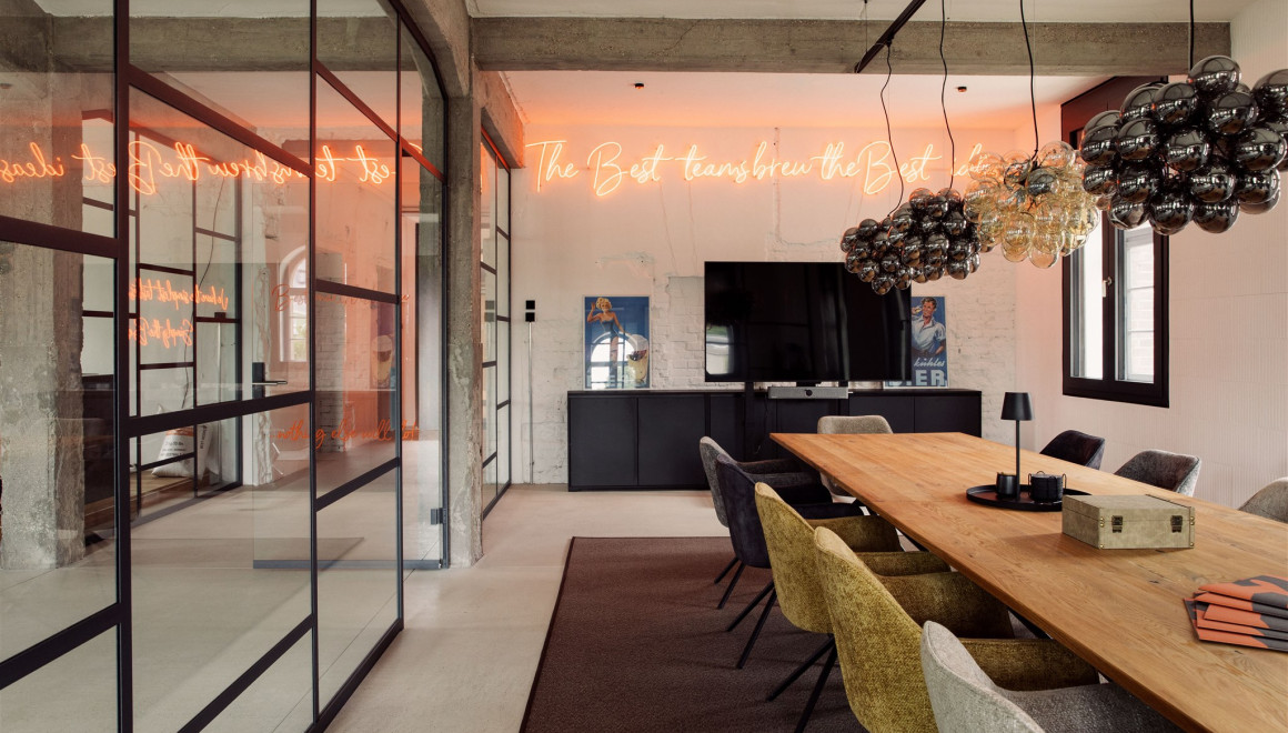 Meetingraum mit eleganter Beleuchtung, einem langen Holztisch und Glasfront