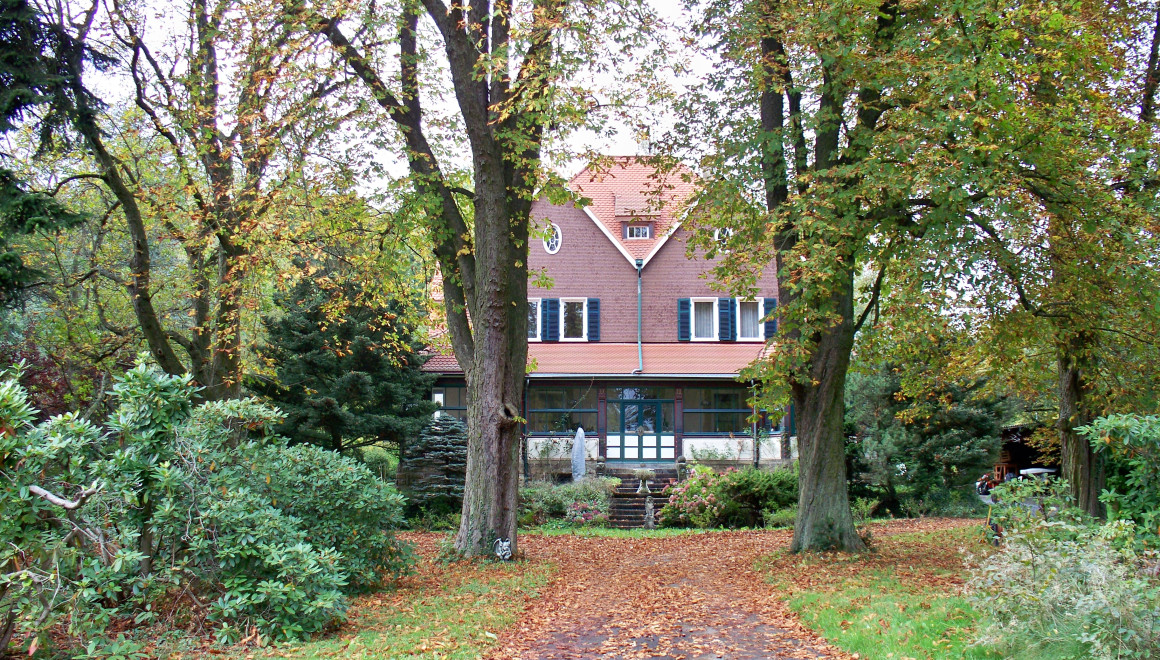 Das Bild zeigt die Frontansicht unseres Hauses von der Straße her kommend. Es zeigt die Auffahrt sowie den an der Frontseite des Hauses gelegenen Wintergarten.