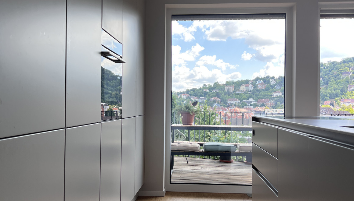 Sandgraue, moderne Küchenfronten mit Blick auf ein großes Fenster